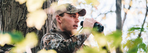Birdwatcher usando il suo binocolo in una foresta
