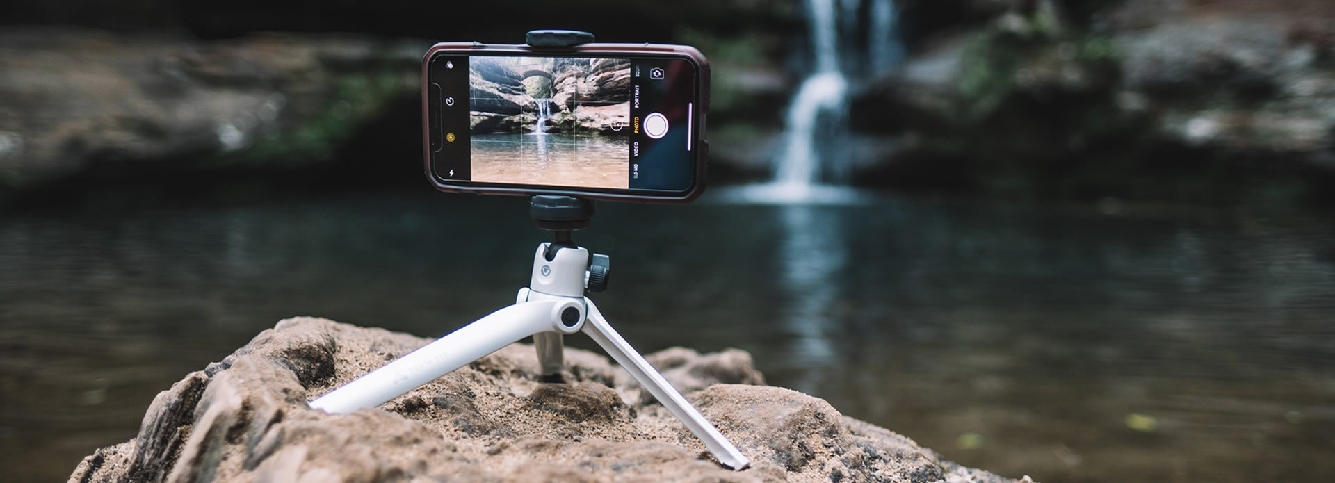 Mini treppiede per smartphone con un telefono cellulare in cima a scattare una foto di una cascata