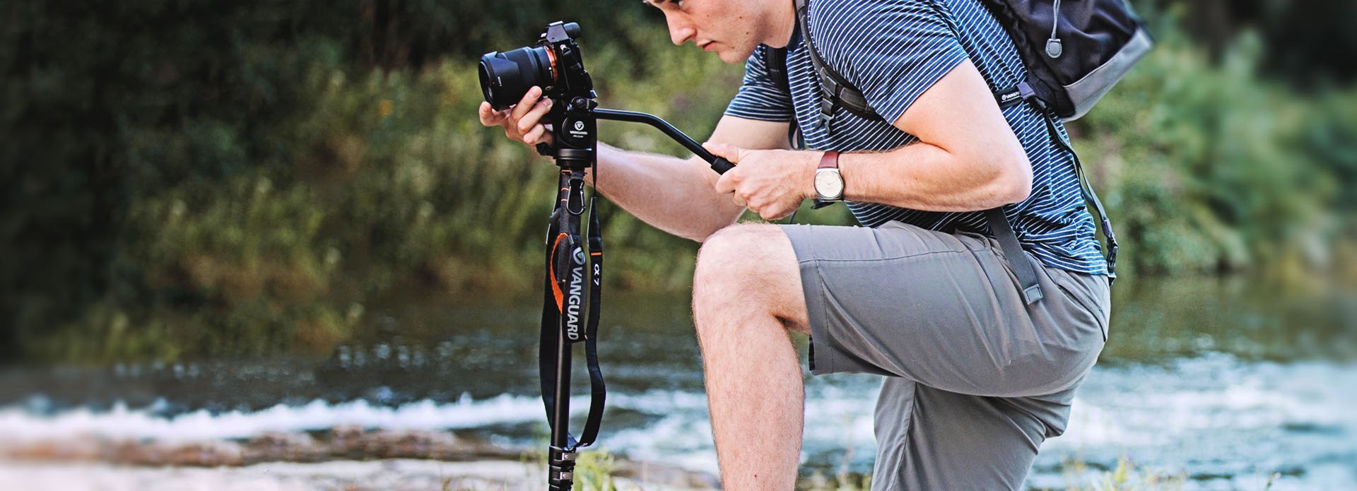 Fotografo che usa la sua macchina fotografica su un monopiede con una testa video accanto a un fiume